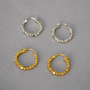 Détail de boucles d'oreilles créoles à perles facettées plaquées or et argent avec fermoir