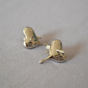 Détail macro des boucles d'oreilles cœur en métal liquide avec effet de fusion argenté