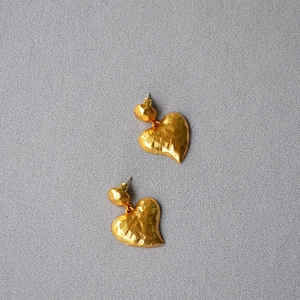 Close-up of hammered gold texture on irregular heart-shaped earrings with vintage finish