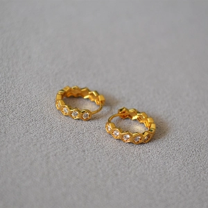 Détail de boucles d'oreilles hexagonales dorées avec zircons étincelants style nid d'abeille