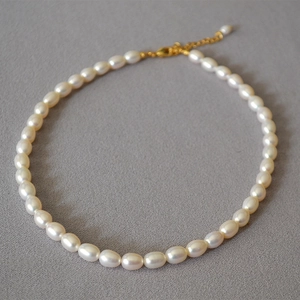 Dettaglio collana di perle d'acqua dolce con chiusura a moschettone dorata e catenella