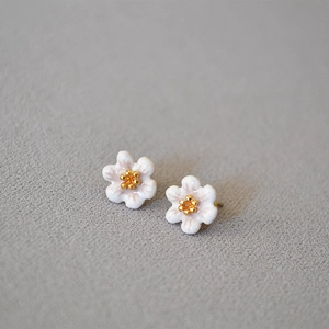 Macro detail of handmade enamel camellia earrings with pink petals and gold stamens