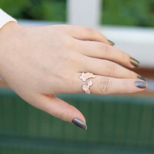 Close-up of pink enamel cherry blossom adjustable ring on model's hand in daylight