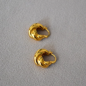 Détail de boucles d'oreilles créoles torsadées en laiton plaqué or avec fini poli