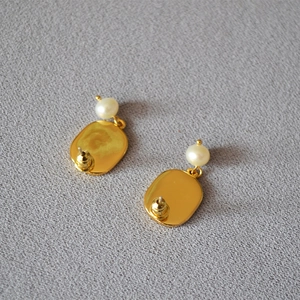 Close-up of handmade chamomile pearl earrings with golden finish and 925 silver pins