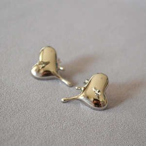 Détail macro de boucles d'oreilles cœur en métal liquide argenté avec fini poli