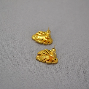 Close-up of golden palm leaf stud earrings with textured finish and zircon inlays