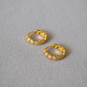 Boucles d'oreilles minimalistes dorées en nid d'abeille avec zircons sur fond gris