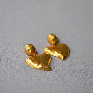 Close-up of vintage hammered texture on gold-plated heart-shaped drop earrings