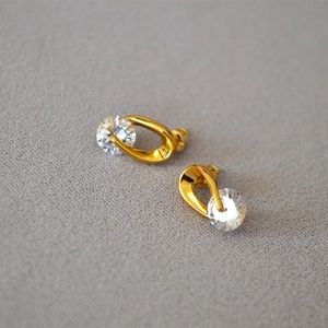 Macro view of gold plated twisted earrings with sparkling round cubic zirconia stones