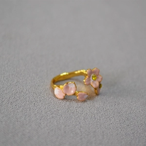 Detailed view of the pink enamel cherry blossom petal and adjustable golden band ring