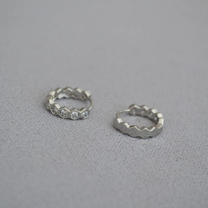Gros plan de boucles d'oreilles hexagonales argentées avec pierres en zircone cubique