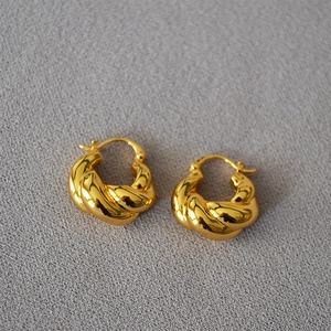 Détail de boucles d'oreilles torsadées en laiton doré avec une finition miroir poli