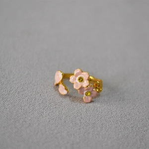 Close-up of pink enamel cherry blossom open ring with yellow gemstone on gold band