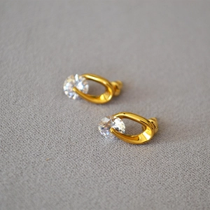 Detailed macro view of U-shaped gold stud earring with sparkling round-cut zircon stone