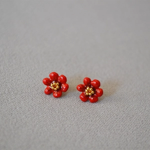 Macro view of handmade red enamel camellia stud earrings with golden pistils