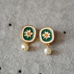 Close-up of enamel daisy earrings with freshwater pearls and gold-plated finish