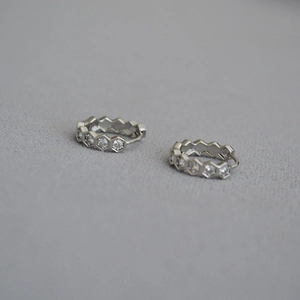 Détail de créoles hexagonales en argent avec zircons blancs ronds en forme de nid d'abeille