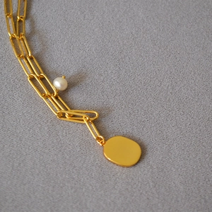 Golden paperclip chain necklace with a round white pearl and oval polished pendant
