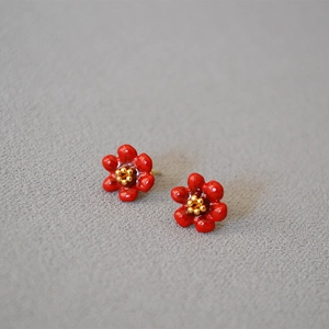 Macro view of red enamel camellia stud earrings with golden beaded stamen details