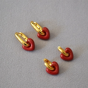 Detail of red enamel heart earrings with gold metal hoops in two different sizes