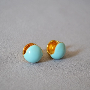 Close-up of sky blue enamel drop earrings with elegant gold-plated brass hoops