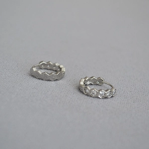 Détail macro des boucles d'oreilles hexagonales en argent serties de zircons