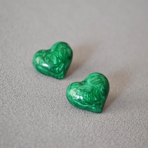 Green heart earrings with marble texture and polished finish on a gray background