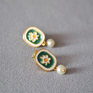 Close-up of vintage enamel chamomile earrings with freshwater pearl drops on 925 silver