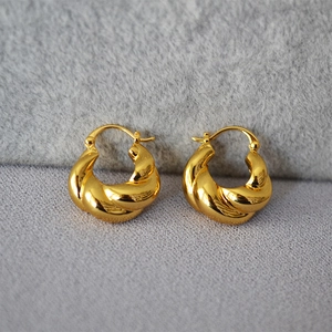 Détail macro de boucles d'oreilles créoles torsadées plaquées or avec finition miroir poli