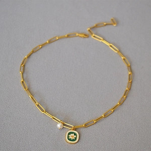Detail of a paperclip chain necklace with green enamel daisy and pearl pendants