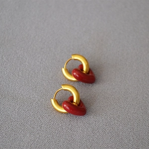 Detailed view of gold hoop earrings with red heart pendants and glossy enamel finish