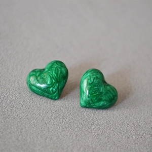 Close-up of green marble-textured heart stud earrings with a glossy resin finish