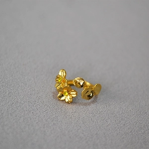 Macro view of adjustable gold ring featuring pink enamel cherry blossoms and yellow zircon