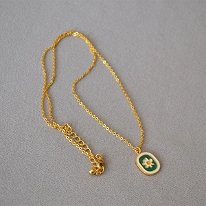 Detail view of vintage enamel daisy pendant on a delicate gold chain necklace