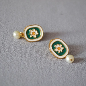 Detail of vintage enamel daisy earrings with green finish and white freshwater pearl