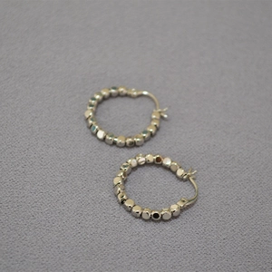 Vue détaillée de boucles d'oreilles créoles argentées avec perles en métal à multiples facettes