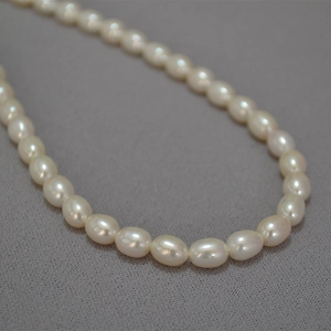 Elegante collana di perle d'acqua dolce ovali in stile francese su un tessuto grigio