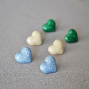 Detail of heart-shaped pearl enamel earrings in blue, white, and green marble textures