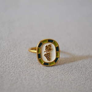 Detailed macro shot of vintage oval brass ring with gold grape patterns and enamel finish