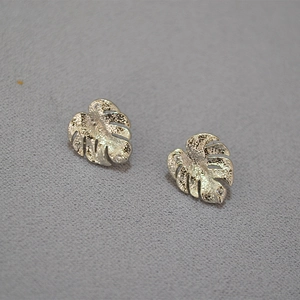 Detailed view of silver palm leaf earrings with sparkling cubic zirconia on grey background