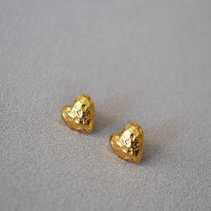 Macro detail of golden hammered texture heart-shaped earrings with reflective finish