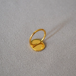Detailed view of a minimalist gold-plated brass ring with a flat round surface