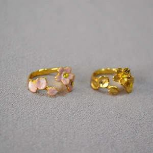 Detailed close-up of pink enamel cherry blossom ring with gold finish and yellow crystals