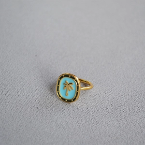 Detail of vintage gold ring featuring blue enamel palm tree and studded black border