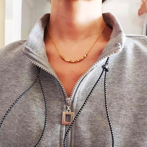Close-up of minimalist gold plated beaded necklace worn on neck with metallic shine
