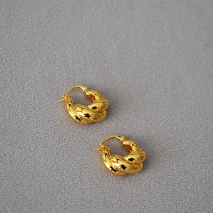 Gros plan détaillé des boucles d'oreilles torsadées dorées avec texture spirale