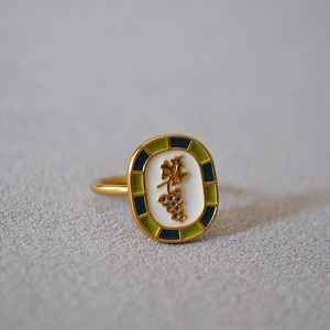 Macro shot of vintage gold brass ring with grape relief and blue-green enamel border