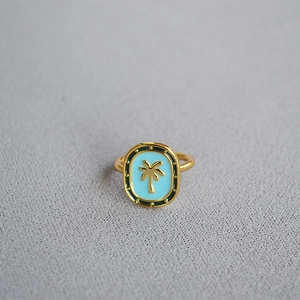 Macro detail of gold-plated ring featuring light blue enamel and palm tree relief