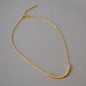 Detailed macro view of 18K gold plated faceted square beads on a dainty choker necklace